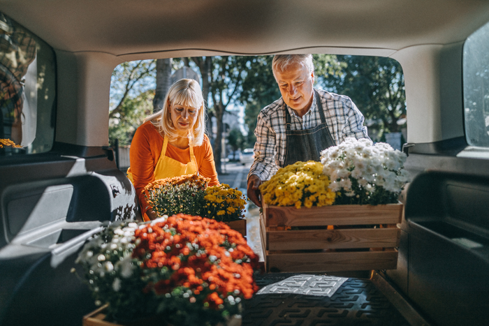 Couple unloading crates of fresh flowers from car trunk