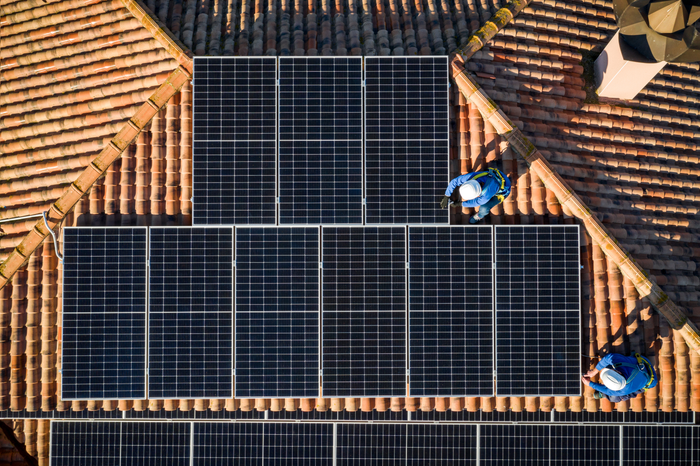 aerial view of Two workers installing solar panels on a rooftop