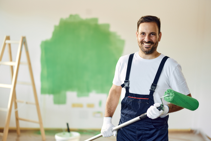 Happy house painter working on home renovation process.