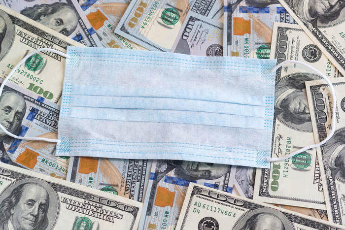 The disposable medical mask is on top of the hundred-dollar bills. Protecting businesses during the covid-19 coronavirus epidemic