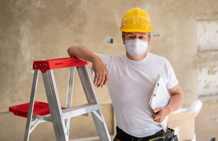 Construction worker remodeling a house and wearing a facemask