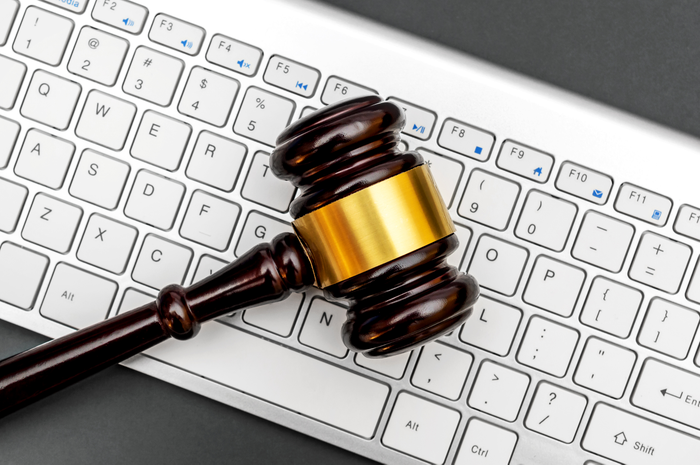 Judge's gavel with computer keyboard on grey background. Top view.